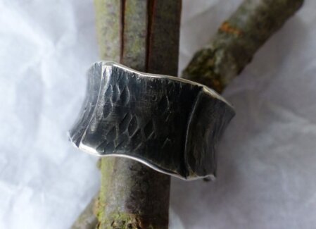 Hammerschlag-Ring geschwaerzt Ring aus gehaemmerten, überlappenden Platten. Konkav. Geschwaerzt. Breite 12 mm. Ringgroesse 60.