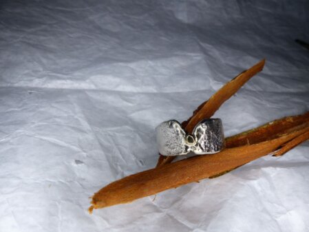Ring mit Goldnugget Ring mit geschmorten Fronten und aufgeloetetem Goldnugget. Geschmort, wellige Kanten. Breite 10 mm. Die Ringgroesse ist 60.